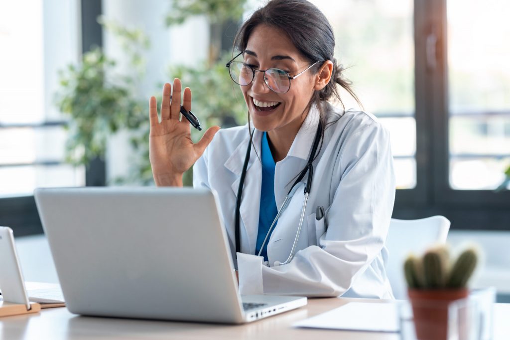 Ways healthcare professionals can improve telehealth appointments for patients, female doctor waving and smiling during telehealth appointment