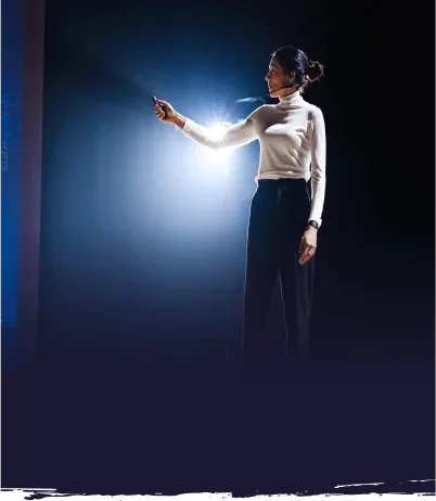 woman in the spotlight on stage delivering a speech.